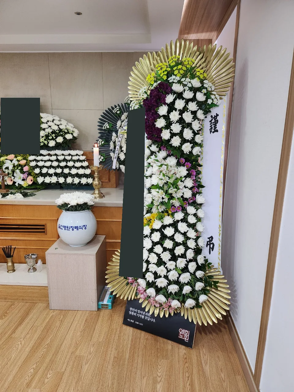 빈소 내부에 배치된 예도 근조화환과 하단 브랜드판